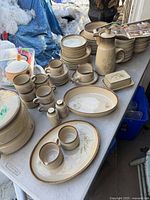 Full layout of plates, bowls, mugs, platters, tureen and serving pieces on folding table