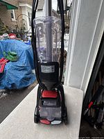 Front view of the Hoover PowerDash Compact carpet cleaner showing the clear water tank and power cord.