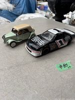 Two car models on a table, porcelain Citroen model and metal Thunderbird race car model.