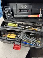 Opened black plastic toolbox displaying all contents including hammer, screwdrivers, pliers, utility knives, wrench, hex keys and drill bits