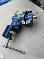 Blue metal vice clamped to a surface showing the handle and jaws.