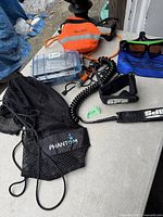 Photo showing the surf leash coiled cord, ankle strap, the black Phantom mesh bag, and orange Scotty pouch with reflective stripes.
