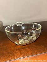 Close-up photo of one clear glass bowl with bubble grape cluster detail on the side, showing the glass texture and grape bubble design.