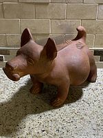Front side of ceramic Colima dog sculpture showing detailed facial features and corn in mouth.