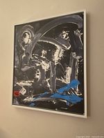 Frontal view of original abstract pop art painting showing black, white, grey strokes with blue and red accents in white frame.