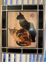 Full view of stained glass panel showing two cats framed in leaded black glass border.
