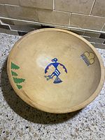 Top view of the wooden bowl showing the painted bird, trees, and cloud designs inside the bowl.
