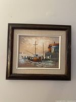 Frontal view of the framed oil painting showing docked boats in front of a pier with buildings under a cloudy sky.