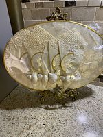 Set of 4 white lace handkerchiefs displayed with 5 Capiz shell napkin rings on an ornate metal stand inside a Capiz shell placemat.