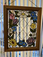 Front view of stained glass framed wall hanging showing floral border with multiple colored flowers and lattice design.
