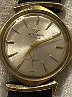 Front view of silver dial showing gold-tone indices, hands, subsidiary seconds and Wittnauer Genève logo