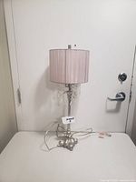Full view of the lamp showing metal base, fabric shade and power cord.