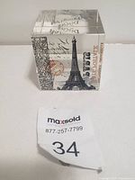 Clear glass cube with Eiffel Tower image and postal stamp design from front angle on white background