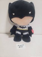 Front view of Batman plush toy showing the entire figure from head to foot in black and grey with yellow accents.
