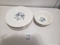 Image showing stack of white dinner plates with blue floral design along with matching bowls in good condition