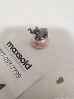 Close-up photo of small silver-tone elephant figurine seated on pink marvel stone.
