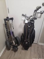 Photo of Wilson golf bag filled with various right hand golf clubs adjacent to Cadie Golf foldable cart