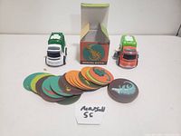 Memory matching game cards and two toy dump trucks sitting on a white surface with the matching game box behind them.