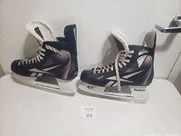 Pair of men's black and gray Reebok ice skates, size 12, side view showing profile and laces