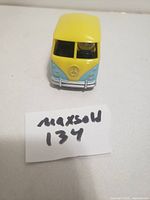 Front view of the Minions cartoon metal toy van showing yellow and pale blue paint with Minions character visible inside through windshield