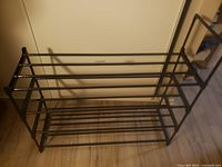 Side view of black metal shoe rack showing multiple horizontal tiers and rectangular shape