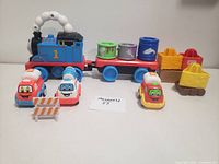 Photo of Thomas train engine with attached trailers and small toy cars in front