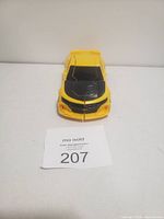 Yellow transformer toy car with black detailing resembling a beetle, displayed in car mode from front angle.