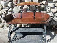 Full view of wood bench seated on removable boot rack against stone wall