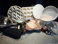 Various mixing bowls, metal baking molds, cake pans, cooling racks, and oven mitts arranged on a counter.