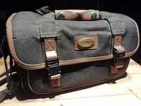 Closed front view of black Canon camera bag with brown trim and buckle straps