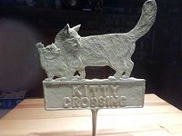 Front view of cast iron Kitty Crossing lawn sign showing two detailed cats and text.