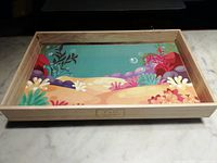 Full view of wooden serving tray with colorful ocean floor illustration inside base.