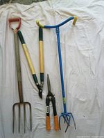 Full view of all four garden tools laid out: garden fork, Fiskars lopper, pruning shears, and garden claw