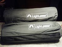 Two Light Speed branded sleeping mats rolled up side by side inside black bags, viewed from above.