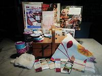 Full lot arranged showing wooden sewing box, multiple sewing patterns, rolls of ribbons, folded fabric, lace, and trims.
