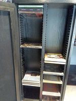 View inside the repurposed speaker showing metal rails and shelves holding CDs and empty spaces.