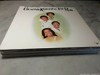 Stack of vinyl albums with Gladys Knight & The Pips album on top, showing front cover with four band members in white attire on a white background.