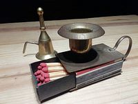 Photo of both vintage brass candle holder with matchbox and matching candle snuffer on wooden surface