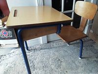 Side view of vintage MidCentury retro school desk showing wood desktop with built-in handle and attached adjustable wooden chair with steel frame.