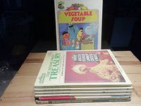 Seven Sesame Street hardcover books stacked with Vegetable Soup book shown upright with cover art of Ernie and Bert cooking and Cookie Monster dreaming of cookies.