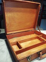 Open vintage wooden artist box showing interior compartments designed for holding paints and brushes.