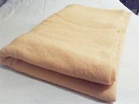 Folded yellow blanket on a white surface showing thickness and texture.