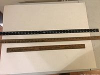 Top view of all three vintage measuring sticks laid next to each other on a white surface showing their lengths and material types.