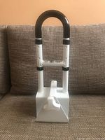 Front view of the white and black adjustable bathtub grab bar with padded handle and locking knob conditions visible.