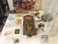 Photo showing assorted vintage barware including branded glasses, beer steins, Miller bottle opener, corkscrews, pour spouts, and bartender books on display.