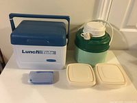Front view of all items including Rubbermaid Lunch Tote cooler, vintage water jug, two beige containers, and small blue ice pack