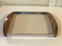 Full view of rectangular mid century tray showing the combination of teak wood curved side handles and polished metal longer sides and base.
