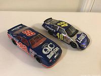Two NASCAR diecast cars, Lowe's #48 and Ford Credit #88, side view showing full length and details.