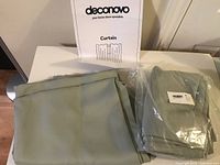 Two curtain panels packaged and unfolded, one folded in soft fabric, other in plastic wrapping with barcode label.