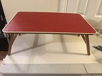 Full view of the folding bed tray showing red top and wooden legs